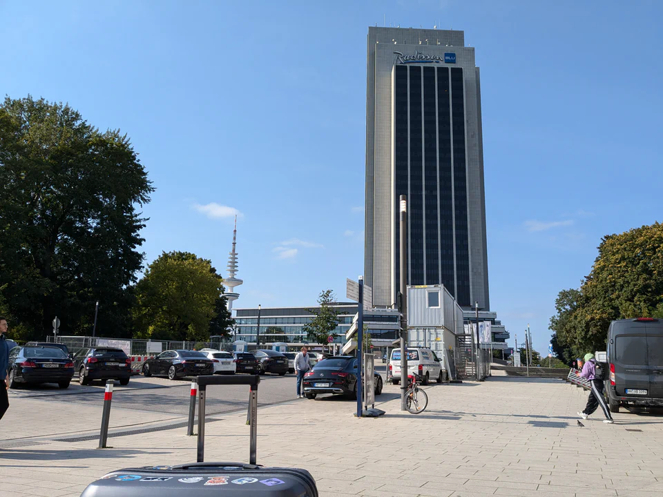 Photo of the large Radisson Blu hotel tower, with the CCH convention center next to it, and my luggage in the foreground