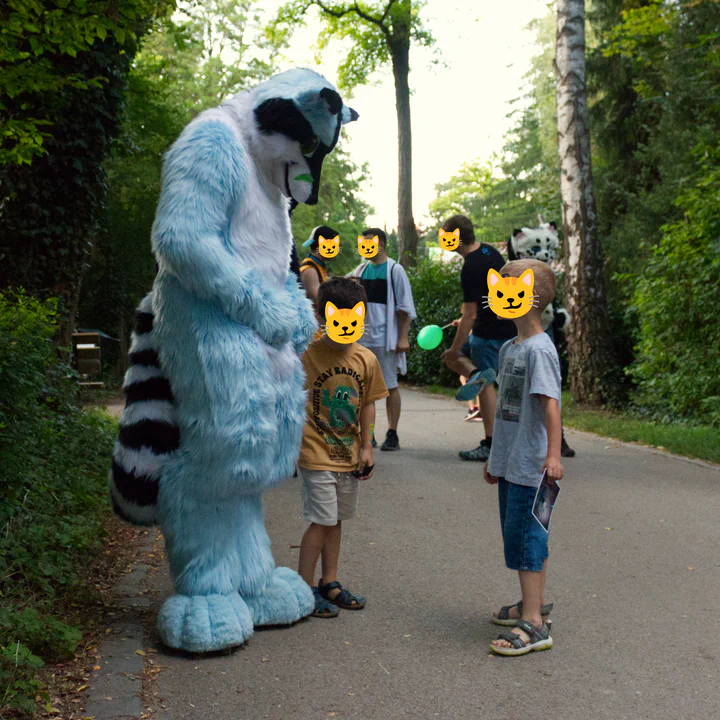 A blue raccoon fursuiter standing next to two children