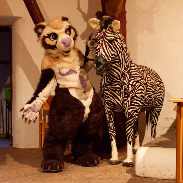 A bear fursuiter standing next to a life-sized zebra figure